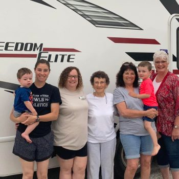 Edythe Nannemann stands with her family in front of an RV.