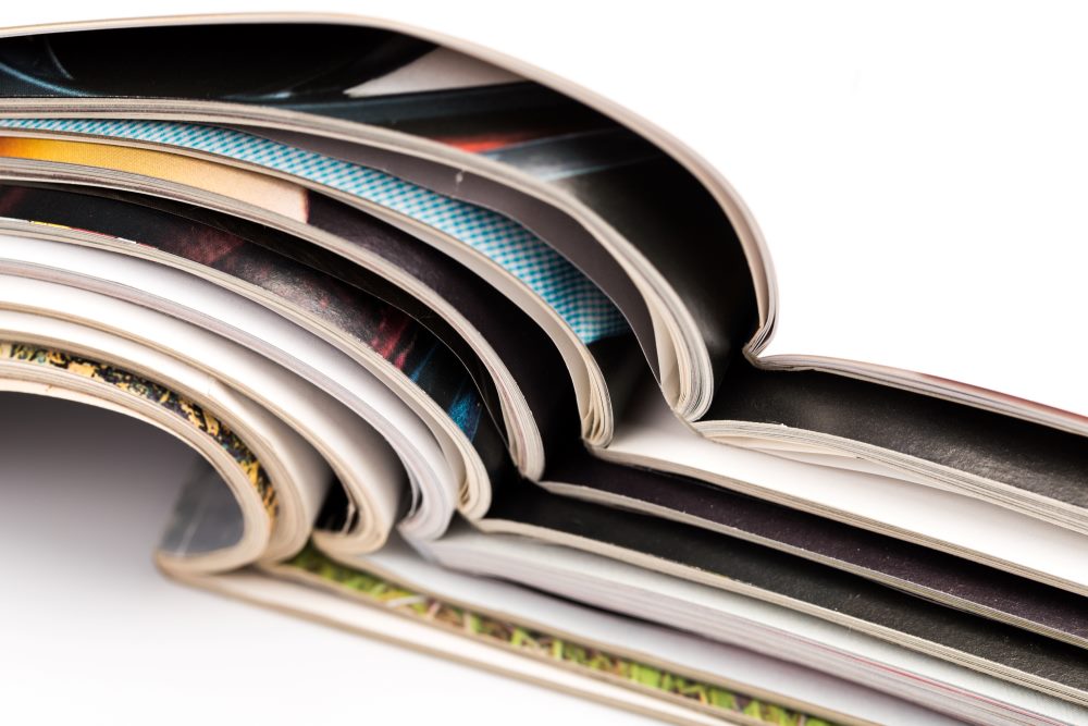 A stack of open magazines on a white surface